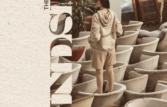 Model wearing the beige brushed-cotton hoodie and shorts from Mindset's 'Urban Flow' collection, standing in an artistic urban installation.